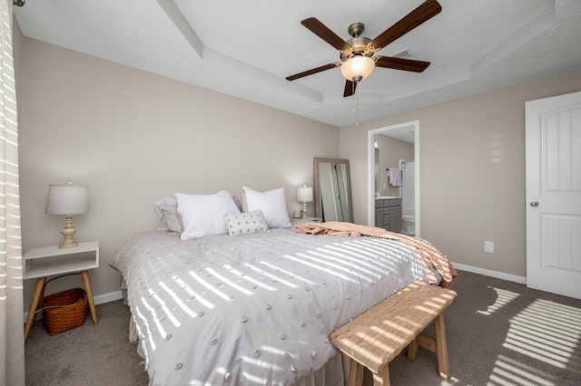 carpeted bedroom with ceiling fan, a raised ceiling, and ensuite bathroom