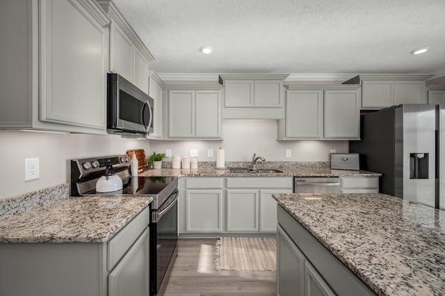 kitchen featuring a textured ceiling, light stone countertops, light hardwood / wood-style flooring, stainless steel appliances, and sink