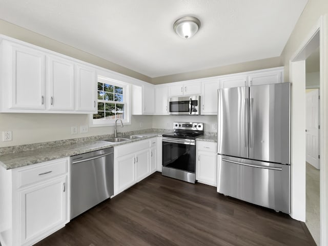 kitchen with dark wood-type flooring, sink, appliances with stainless steel finishes, and white cabinets