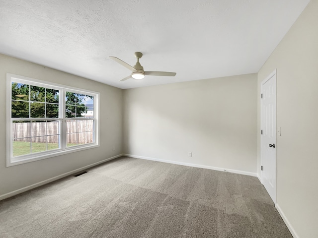 carpeted empty room featuring ceiling fan and a textured ceiling