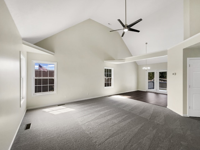 unfurnished living room featuring ceiling fan with notable chandelier, high vaulted ceiling, and dark carpet