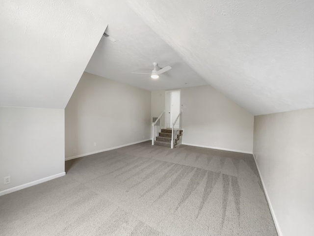 additional living space featuring vaulted ceiling, a textured ceiling, ceiling fan, and carpet floors