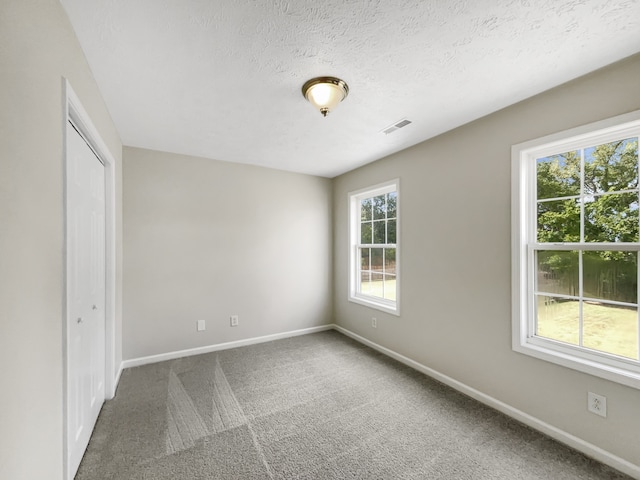 empty room featuring a textured ceiling and carpet floors