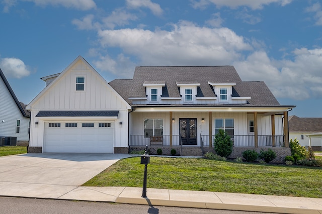 view of front of property featuring a front lawn, a garage, central AC, and covered porch