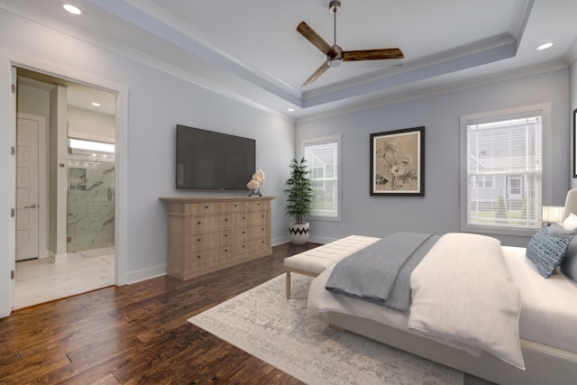 bedroom featuring ceiling fan, ornamental molding, dark wood-type flooring, a tray ceiling, and ensuite bathroom