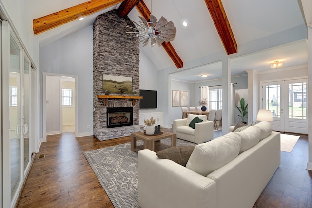 living room featuring a stone fireplace, ceiling fan, beamed ceiling, and dark wood-type flooring