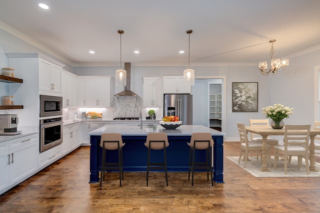 kitchen with appliances with stainless steel finishes, wall chimney exhaust hood, and white cabinetry