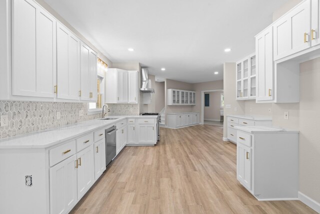 kitchen featuring light wood-type flooring, backsplash, appliances with stainless steel finishes, white cabinets, and wall chimney range hood