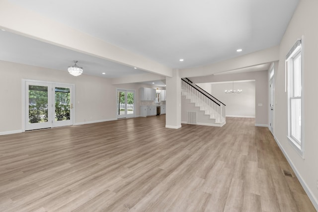 unfurnished living room with an inviting chandelier, recessed lighting, baseboards, and light wood-type flooring