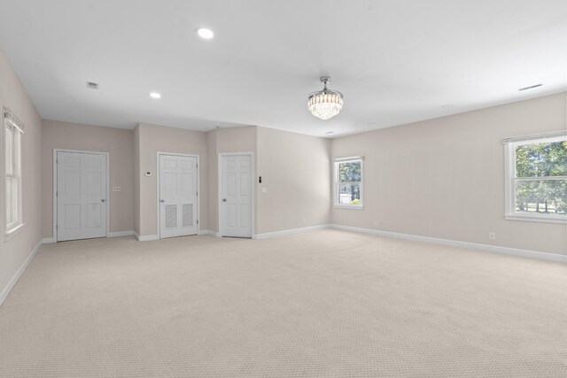 empty room featuring a notable chandelier and light colored carpet