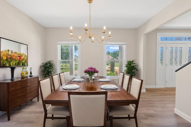 dining space with baseboards, light wood-style floors, and an inviting chandelier