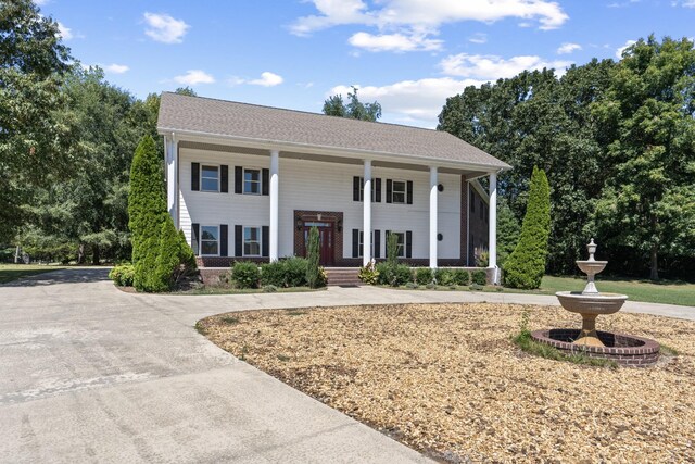 neoclassical home featuring a porch and driveway