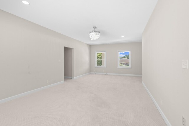 carpeted empty room featuring an inviting chandelier