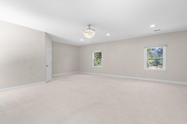 spare room with an inviting chandelier, recessed lighting, light colored carpet, and baseboards