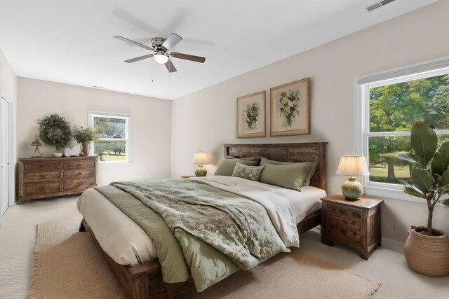 carpeted bedroom featuring multiple windows and ceiling fan