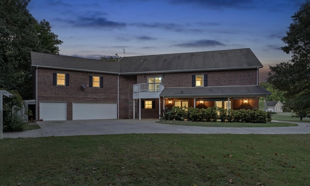 view of front of home featuring a yard, a balcony, a garage, and concrete driveway