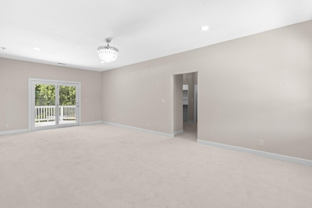 unfurnished room featuring light colored carpet and an inviting chandelier