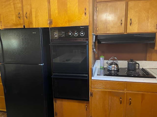 kitchen with black appliances, brown cabinetry, light countertops, and under cabinet range hood