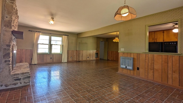 unfurnished living room with heating unit, a wainscoted wall, brick patterned floor, and wallpapered walls