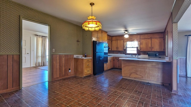 kitchen featuring light countertops, hanging light fixtures, freestanding refrigerator, stainless steel microwave, and wallpapered walls