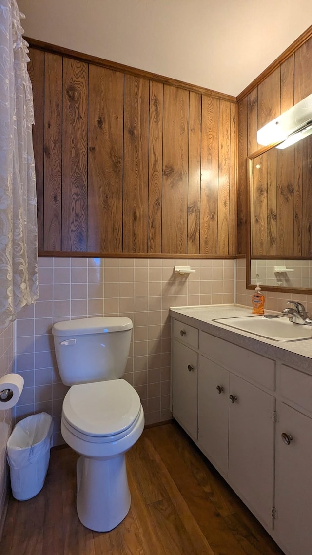 full bathroom with a wainscoted wall, tile walls, toilet, vanity, and wood finished floors