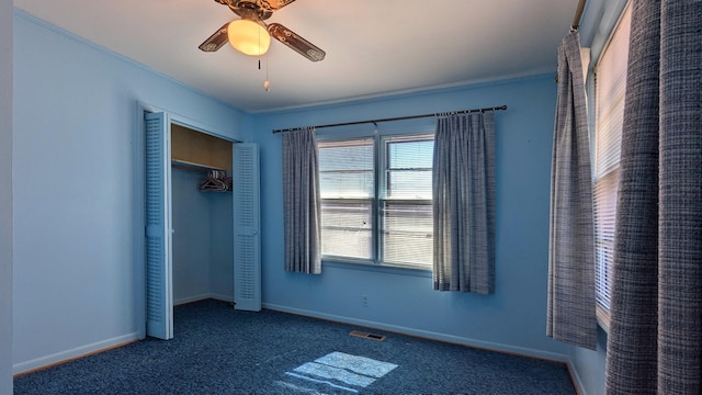 unfurnished bedroom with baseboards, visible vents, ceiling fan, dark carpet, and a closet