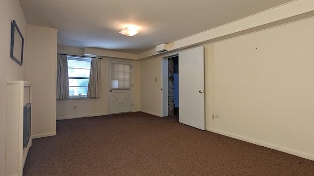 unfurnished room featuring dark colored carpet and baseboards