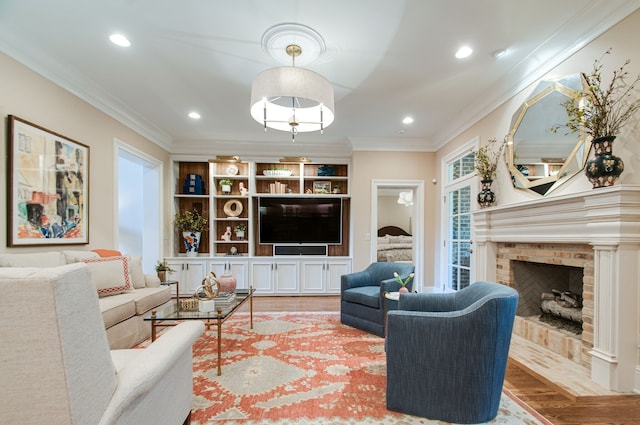 living room with wood-type flooring, ornamental molding, and a brick fireplace