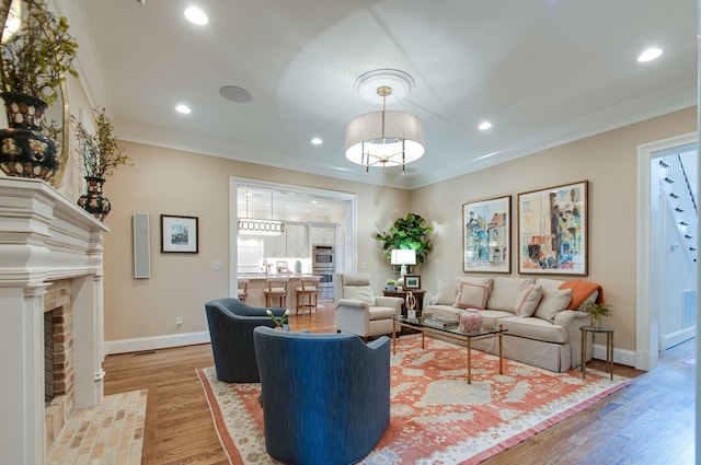 living room featuring crown molding, a brick fireplace, and hardwood / wood-style floors