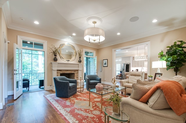 living room with crown molding, wood-type flooring, and a brick fireplace