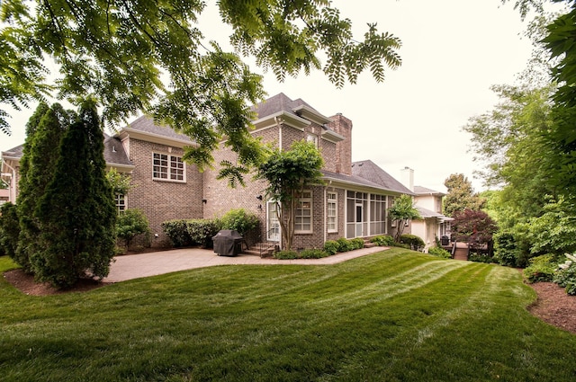 view of front facade with a patio area, a sunroom, and a front yard