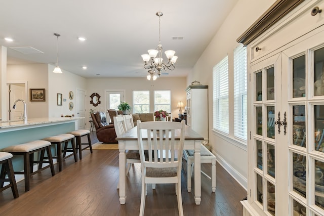 dining area with an inviting chandelier, sink, and dark hardwood / wood-style floors