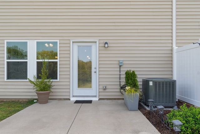 view of exterior entry featuring cooling unit and a patio area