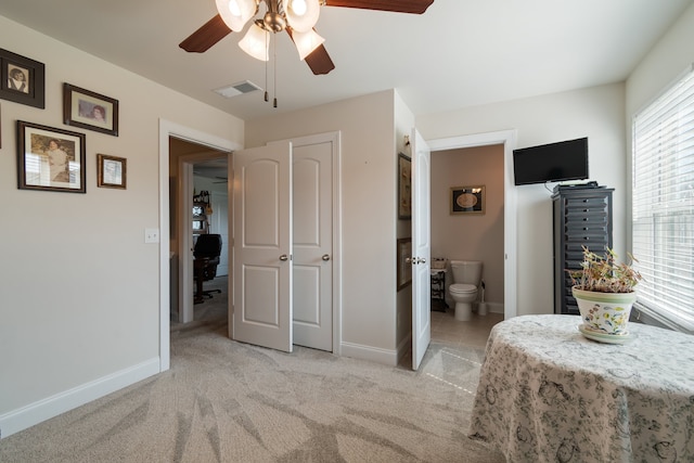 bedroom featuring light colored carpet, connected bathroom, and ceiling fan