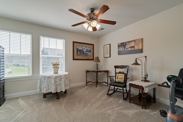 living area featuring a healthy amount of sunlight, ceiling fan, and light colored carpet