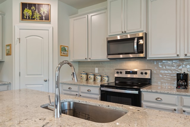 kitchen featuring backsplash, light stone counters, stainless steel appliances, and sink