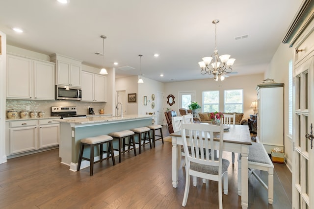 dining space with a notable chandelier, sink, and dark hardwood / wood-style flooring