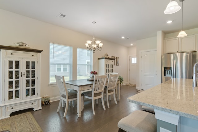 dining area with dark wood-type flooring and an inviting chandelier