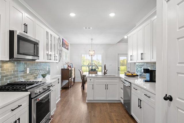 kitchen with dark hardwood / wood-style floors, pendant lighting, stainless steel appliances, sink, and white cabinets