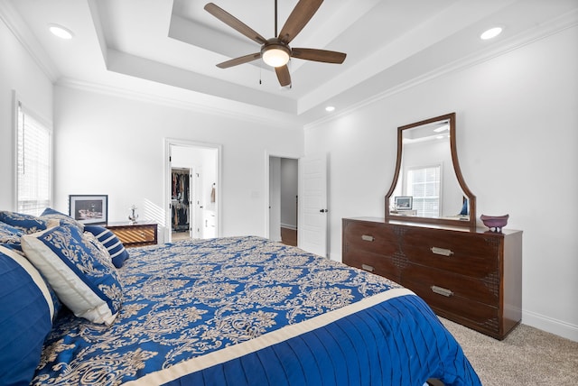 bedroom with a tray ceiling, crown molding, light colored carpet, and ceiling fan