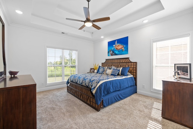 bedroom with a tray ceiling, crown molding, light carpet, and ceiling fan