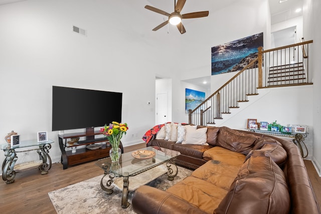 living room featuring ceiling fan, hardwood / wood-style flooring, and a high ceiling