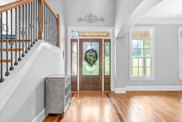 entrance foyer featuring stairway, crown molding, baseboards, and wood finished floors