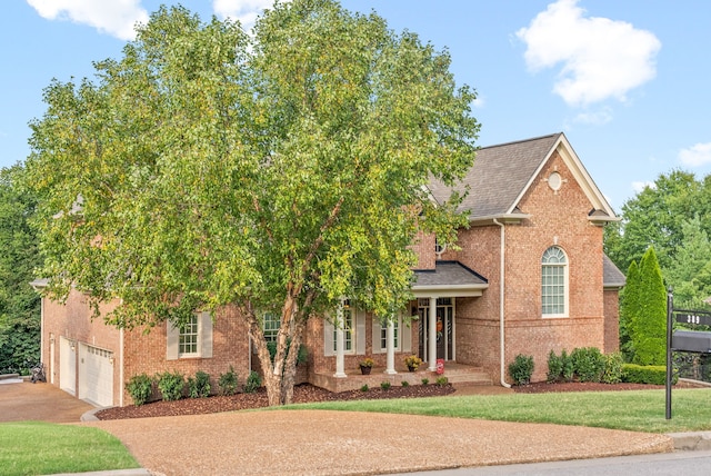 view of property hidden behind natural elements with a garage and a front lawn