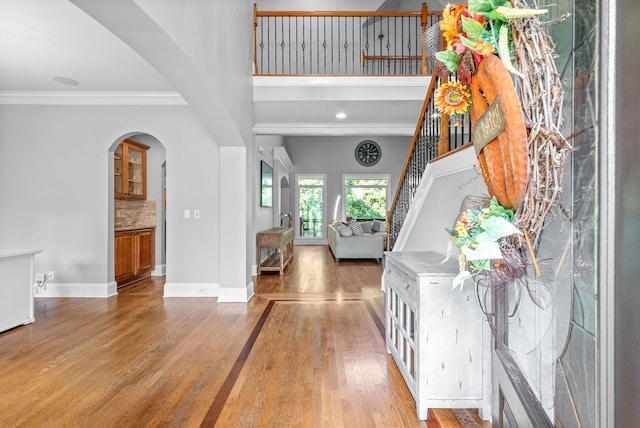 entryway with baseboards, stairway, ornamental molding, wood finished floors, and arched walkways