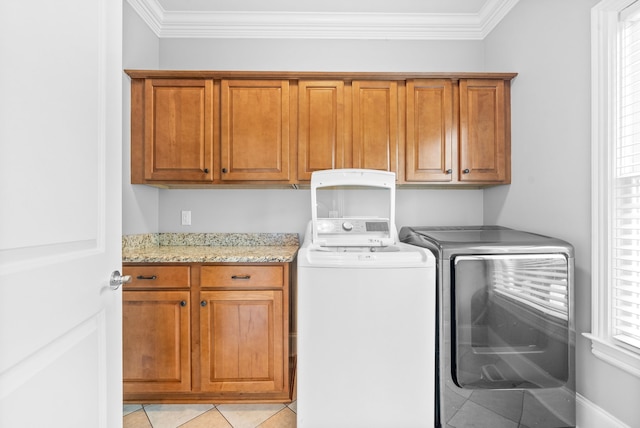 laundry area with light tile patterned floors, cabinet space, ornamental molding, and washing machine and clothes dryer