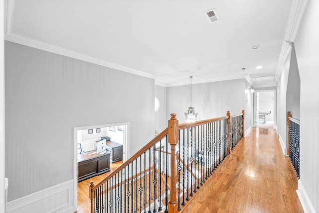 hall with visible vents, crown molding, light wood-type flooring, an upstairs landing, and a notable chandelier