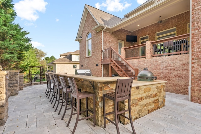 view of patio / terrace featuring stairs, exterior kitchen, and outdoor wet bar