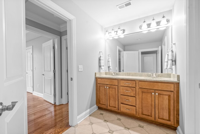 bathroom featuring visible vents, baseboards, double vanity, wood finished floors, and a sink