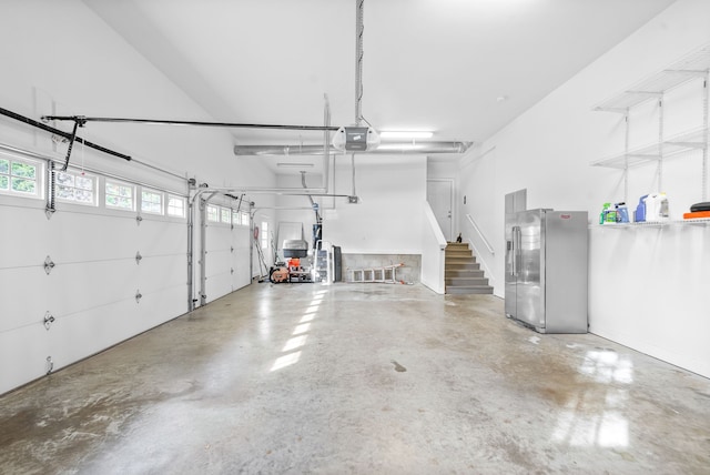 garage featuring a garage door opener and stainless steel fridge with ice dispenser